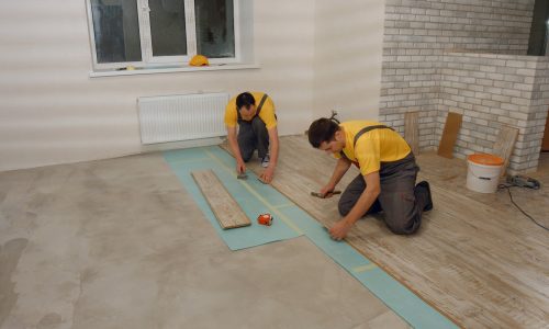Builders laying wooden flooring.